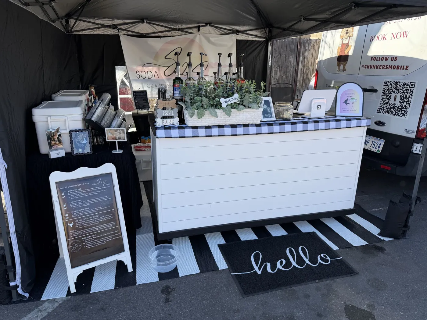 The S2S Soda Bar cart set up with syrups, greenery and a hello mat