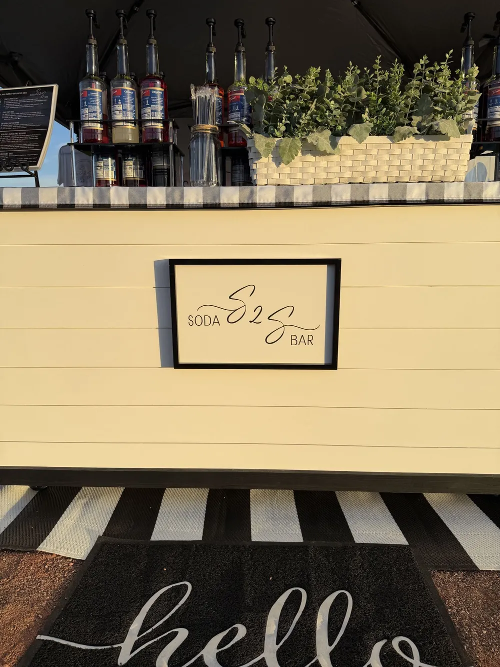 The S2S Soda Bar sign on the front of the white cart