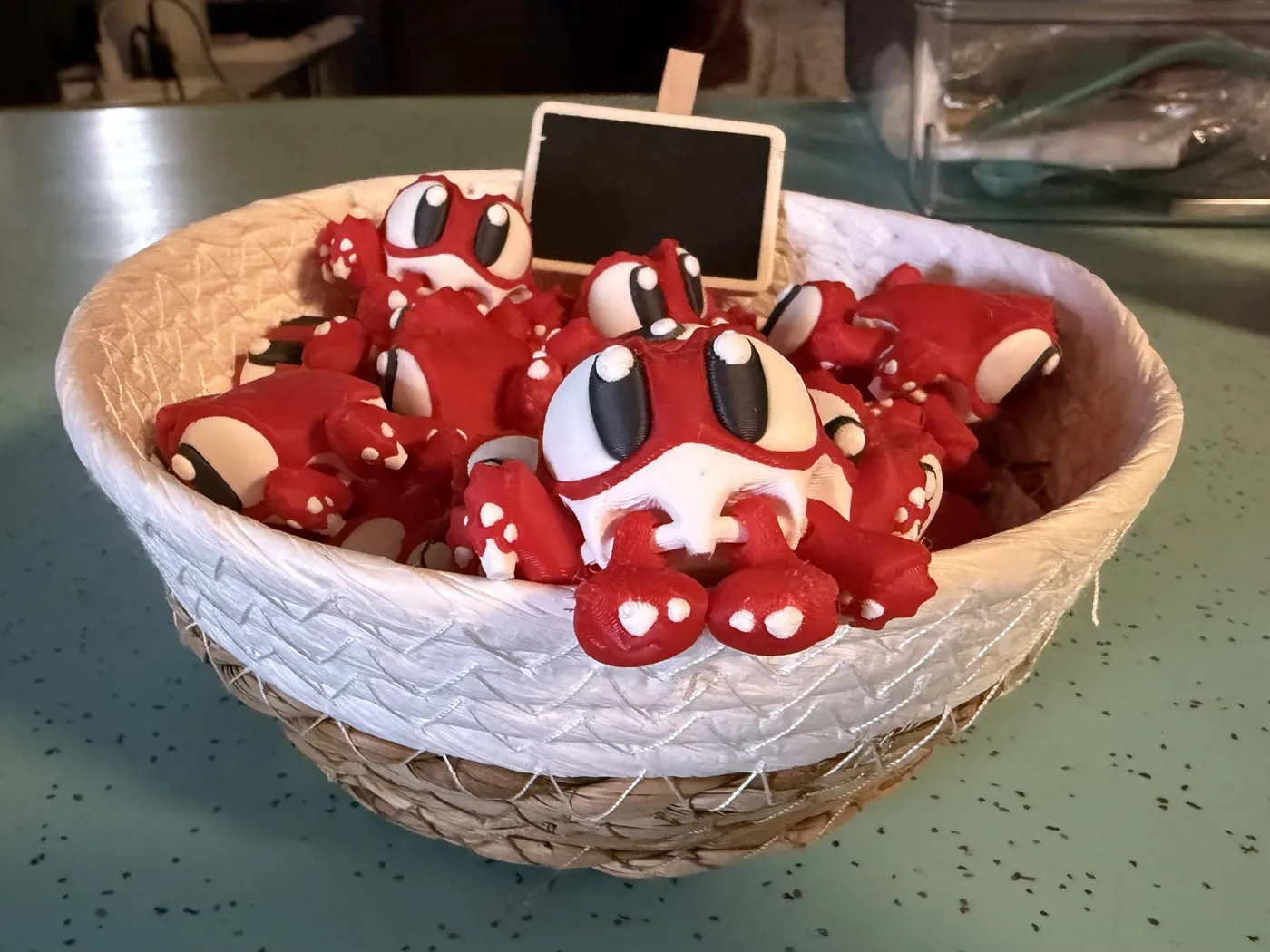 A basket full of red and white 3D-printed frog critters